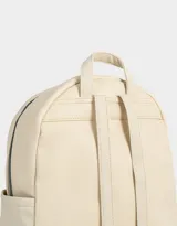 Mochila urbana negra de cuerina con bolsillo frontal con cierre y charm colgante de cadena con dije de corazón y candado. Tiene correas regulables, manija superior, cierre superior, doble bolsillo frontal (uno con charm metálico) y bolsillos laterales.