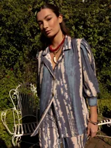 Blazer con estampado tie-dye en tonos azules y beige, con hombros marcados y mangas largas con puño ancho.