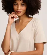 Vestido corto tipo t-shirt color beige, confeccionado en viscolino, con escote en V y mangas cortas. Presenta una estampa de arco de lapa en la falda.