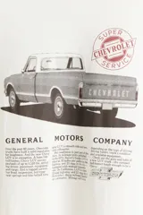 Remera blanca de corte amplio con estampado de camioneta Chevrolet y texto de General Motors.