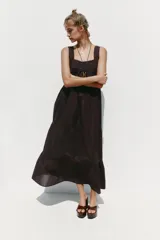 Vestido midi color marrón oscuro, con tirantes anchos y escote recto. Presenta detalle de puntilla en el escote y bordados a tono en el ruedo.