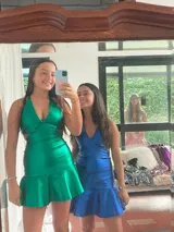 Vestido corto de lentejuelas color verde oliva, con escote en V, breteles finos cruzados en la espalda, cut-outs laterales y volado en el ruedo.