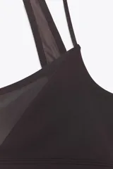 Top negro con escote redondo, tirantes finos ajustables y tejido combinado en tul a tono. Cierre en espalda con gancho metálico.