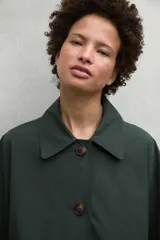 Chaqueta verde oscuro con cuello clásico, cierre con botones y bolsillos laterales.