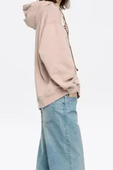 Sudadera rosa de algodón con capucha ajustable con cordones, corte oversize, manga larga y logo bordado.