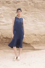 Vestido azul marino de lino, corte recto, sin mangas y largo midi con volado en el ruedo.