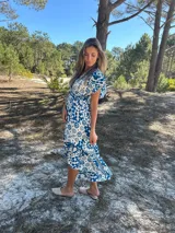 Vestido midi de seda con estampado floral en tonos azul y blanco, escote en V y mangas cortas.
