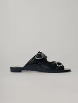 Sandalias planas de cuero color negro, con dos tiras anchas sobre el empeine y hebillas metálicas plateadas.