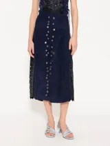 Pollera midi de cuero caprino color azul marino, con vuelo y tela complementaria con bordado de lentejuelas en los laterales. Presenta ojalillos de níquel en el frente y cierre metálico en la espalda.