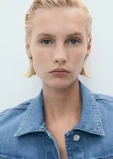 Chaqueta de denim celeste de corte cropped, con cuello camisero, cierre frontal con botones, mangas largas con puños abotonados y dos bolsillos de parche con solapa en el pecho.