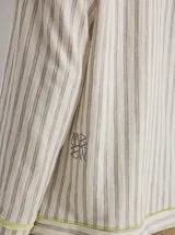 Chomba a rayas horizontales color crudo y gris, con capucha y botones de madera. Tiene cordones de ajuste en la capucha y puños con ribete verde flúor.