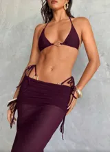 Conjunto de bikini color borgoña, compuesto por un corpiño triangular con detalle de aro dorado y una falda midi de tul con fruncido y detalle de aros dorados.