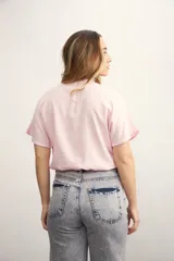 Blusa rosa de lino con escote cruzado en V y mangas cortas. Incluye un collar con cordón negro y dije dorado.