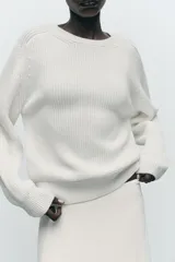 Sweater color blanco de punto perlado, con cuello redondo y mangas largas.
