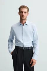 Camisa negra de manga larga con cuello italiano y cierre frontal de botonadura. Presenta un tejido con estructura de fácil cuidado.