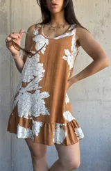 Vestido corto color camel con estampado de flores blancas, sin mangas, con cuello redondo y volados en el ruedo.