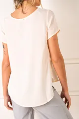 Blusa color crudo de poliéster con mangas cortas y cuello redondo.