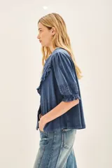 Camisa celeste de algodón con apliques de encaje a tono en pechera y mangas. Cierra con botones de pasta a tono en el frente. Puños con elásticos que generan efecto balloon.