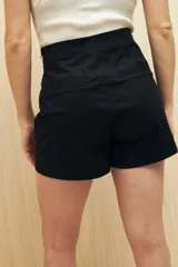 Short pollera color verde militar, de tiro alto, con solapa frontal que simula una falda y bolsillos delanteros.