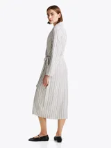Vestido midi cruzado a rayas verticales blancas y grises, con cuello en V, mangas largas y lazo en la cintura.