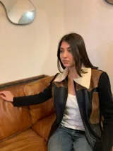 Campera de cuero negra con detalles en cuero marrón y cuello de piel sintética color crema. Mangas largas de tejido de punto negro.