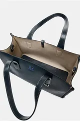 Bolso shopper azul marino con doble asa corta y correa larga de tela color crudo. Tiene detalle de pespuntes blancos y tira con anilla metálica.