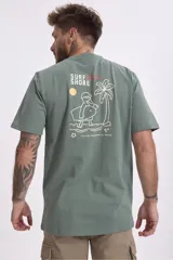 Remera de algodón color verde salvia, con cuello redondo y manga corta. Presenta un pequeño parche estampado en el pecho con un diseño gráfico.