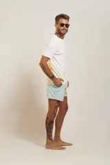 Short de baño para hombre, tiro medio, con estampado tropical en tonos rosados, verdes y blancos. Posee cintura elástica con cordón de ajuste trenzado y bolsillos laterales.