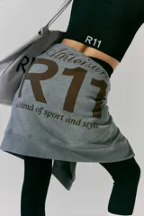 Buzo gris de frisa con capucha, bolsillos delanteros y corte oversize. Tiene recortes laterales, doble cordón con puntera de goma y estampa en frente y espalda.