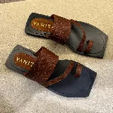 Sandalias chatas de cuero color marrón con base negra y plantilla con el logo de la marca.