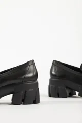 Mocasines negros de cuero con suela track y detalle de borlas.