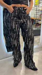 Pantalón de jean negro con estampado abstracto en gris, corte wide leg y tiro alto.