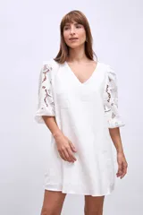 Vestido corto blanco de lino con escote en V y mangas cortas abullonadas con detalles de broderie.