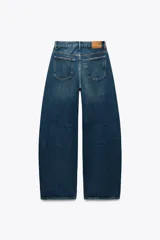 Jeans de tiro medio color azul denim, corte baggy, con trabillas y cinco bolsillos. Cierre frontal asimétrico con cremallera y botones metálicos.