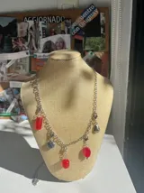 Collar plateado con cadena de eslabones y dijes colgantes con forma de hojas y árbol.