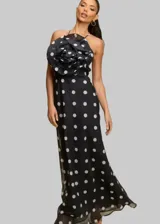 Vestido largo negro con lunares blancos, escote halter con detalle de flor grande en el cuello.