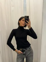 Polera blanca de algodón con cuello alto y mangas largas.