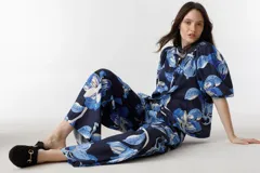 Pantalón culotte de lino azul marino con estampado de flores azules y blancas, tiro alto, cintura con tablas, bolsillos laterales y cierre frontal.