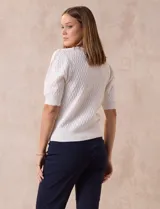 Cárdigan tejido color blanco, marca Tahari. Escote en V, manga corta abullonada con puño y abertura central con botones.