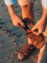 Sandalias de cuero color marrón con tiras anchas entrecruzadas y suela texturizada.