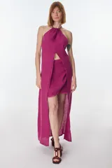Conjunto de top halter con abertura en el abdomen y falda cruzada con ruedo desflecado, color fucsia.