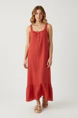 Vestido largo de algodón color rojo, sin mangas y con cuello redondo. Presenta una pechera con botones frontales parciales y un diseño holgado que termina en un ruedo con volado y detalle de puntilla.