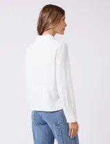 Camisa de crepe color fucsia, con cuello solapa, cierre frontal de botones y dos bolsillos aplicados en el pecho.