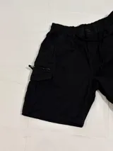Bermuda negra estilo cargo con corte holgado, bolsillos laterales con cierre y cintura elástica.