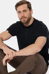 Remera negra de manga corta con cuello mao y tapeta de tres botones oscuros. Presenta un pequeño logo bordado en el pecho y una etiqueta cosida en la manga.