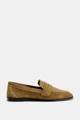 Zapato plano tipo mocasín color marrón claro, confeccionado en piel de serraje. Tiene copete subido, antifaz y punta redonda.