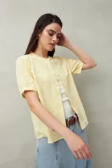 Camisa blanca de manga corta abullonada, cuello mao y botones forrados.
