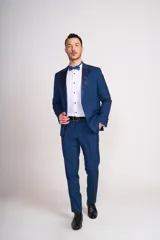 Traje de vestir azul con solapa de satén, compuesto por saco con cierre de un botón, pantalón de corte entallado y moño de satén azul.