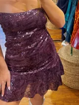 Vestido corto con estampado de rayas horizontales en tonos grises y negros. Diseño con escote halter que se ata al cuello, abertura central en el busto y falda corta con volado.