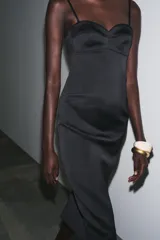 Vestido midi de satén negro con escote corazón, tirantes finos y abertura en el ruedo.